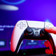 A player holds a PS5 controller in front of a TV.